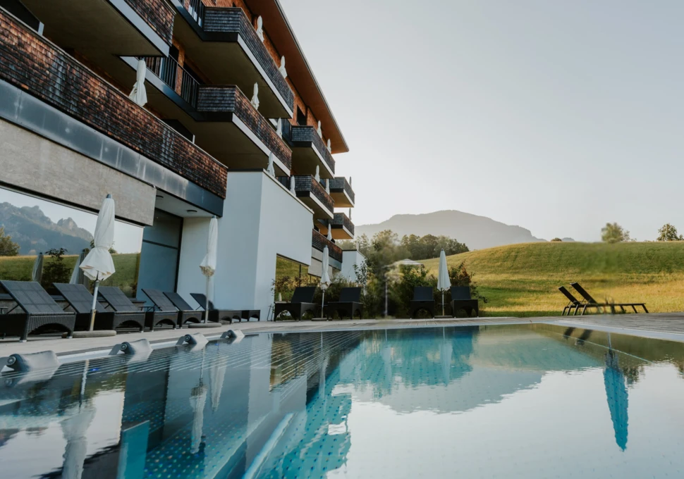 Ein Blick auf den Pool des Hotel Klosterhof, umgeben von einer malerischen Landschaft in Bayerisch Gmain. Entspannung im Wellnesshotel.