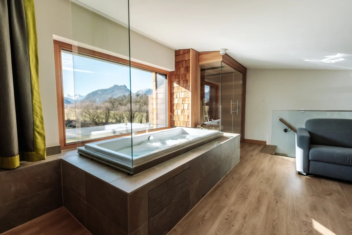 Junge Dame im Whirlpool mit Rosenblättern und Blick aus dem Panoramafenster im Hotel Klosterhof, Bayern.