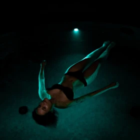 A woman in a black swimsuit floats peacefully in a dimly lit pool at Wellnesshotel Klosterhof in Bayern.